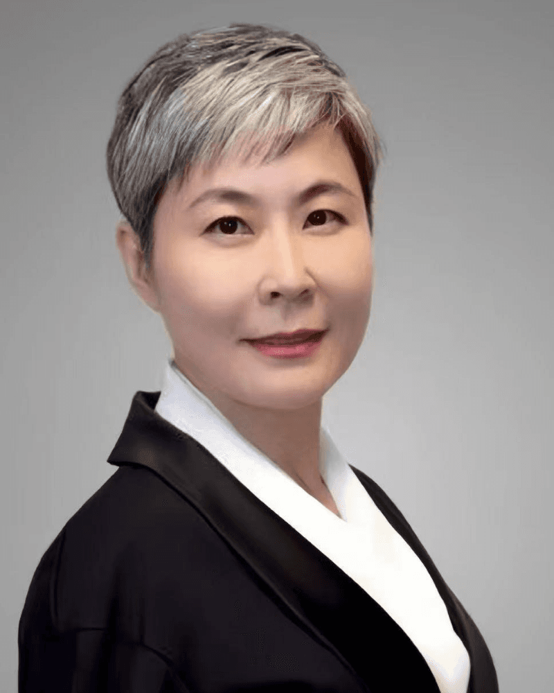 Professional headshot of an Asian woman with short silver hair wearing black and white attire.